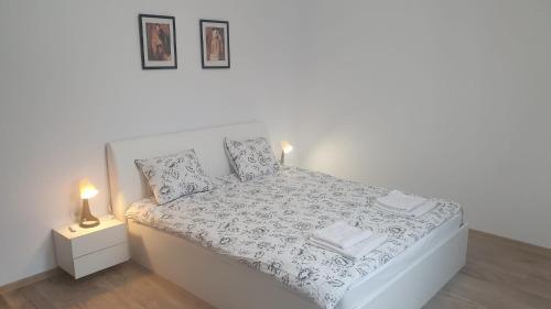 a white bed in a white room with two lamps at MRȘ House 2 in Bucharest