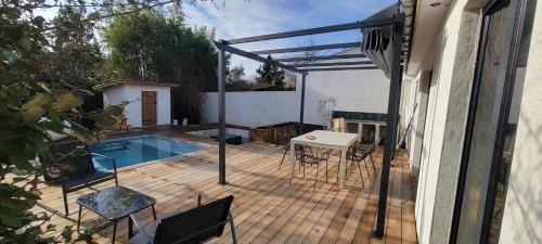 une terrasse avec une piscine, une table et des chaises dans l'établissement Maison familiale avec piscine, à Tresses
