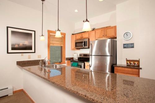 a kitchen with a stainless steel refrigerator and wooden cabinets at River Run Village by Keystone Resort in Keystone