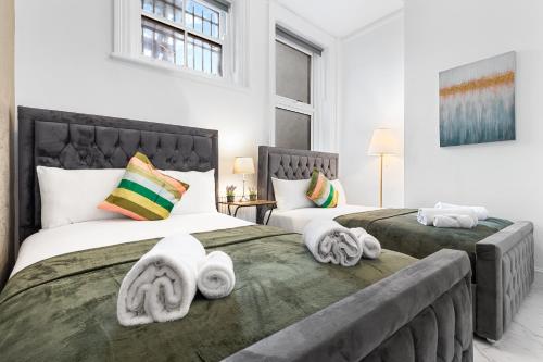 two beds with towels on them in a bedroom at Serviced Modern 1 Bedroom Flat - Sleeps 5 - Near Camden Market, London Zoo, Lord's Cricket Ground - Good Links to King Cross, Euston, Finchley Road Station - NW3 London in London