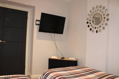 a bedroom with a bed and a flat screen tv on the wall at Railway House in Glossop