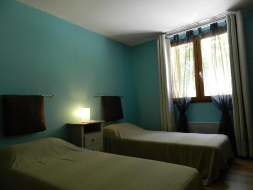 Cette chambre bleue comprend 2 lits et une fenêtre. dans l'établissement HERMITAGE, à Anzex
