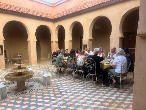 a group of people sitting at a table in a courtyard at Riad Dar Ouzine in Merzouga