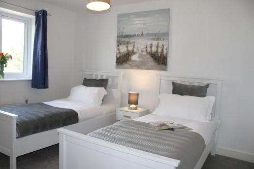 a bedroom with two beds and a painting on the wall at Plush Peterborough in Peterborough
