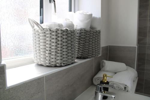 a bathroom with a sink and a basket of towels at Plush Peterborough in Peterborough