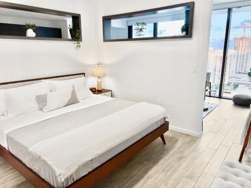 a bedroom with a bed with white sheets and windows at Sleek & Stylish Jr. 1-BR Retreat - Las Olas in Fort Lauderdale