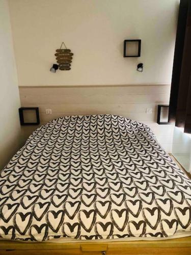 a bed with a black and white comforter in a bedroom at Appartement 6 personnes les terrasses d isola2000 in Isola