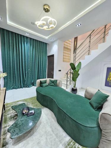 - un grand lit vert dans un salon avec un escalier dans l'établissement Amys_Apartments, à Lagos