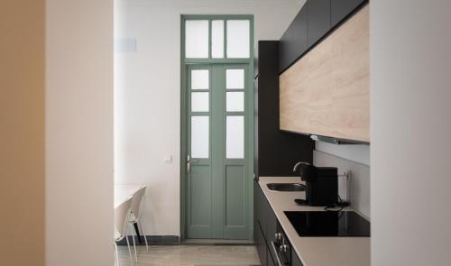 une cuisine avec une porte verte à côté d'un comptoir dans l'établissement REY DE SEVILLA FLATS - Arenal, à Séville