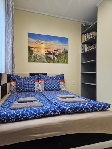 a bedroom with a large bed with blue sheets at Bowery Guest Houses - Árnyas vendégházak in Balatonalmádi