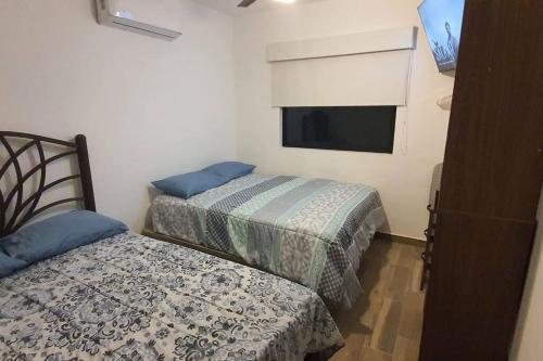 two beds in a small room with a tv at Departamento a 5 minutos de la playa!! in Mazatlán