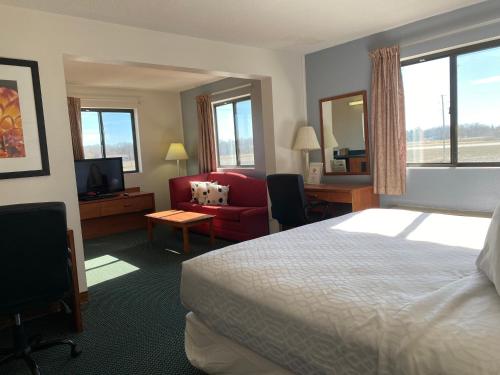 una camera d'albergo con letto, sedia e TV di Carlyle Inn & Suites a Carlyle