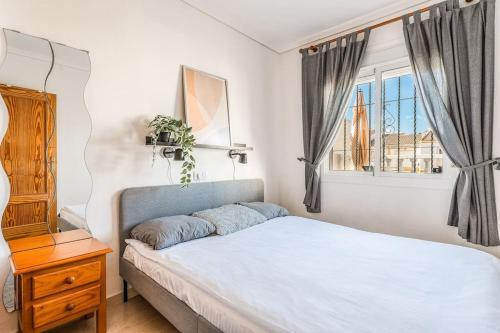 a bedroom with a white bed and a window at Casa Del Sol in Gran Alacant