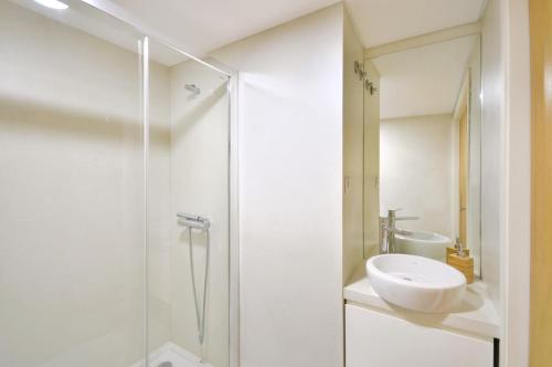 La salle de bains blanche est pourvue d'un lavabo et d'une douche. dans l'établissement Sé do Porto - Loft with City View, à Porto