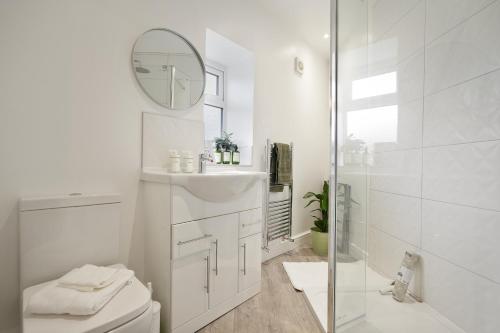 a white bathroom with a toilet and a mirror at Luxury Sheffield Apartment - Your Ideal Home Away From Home in Stannington