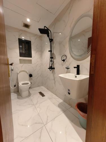 a white bathroom with a sink and a toilet at Ranahouse in Jeddah