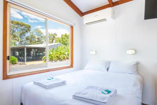 a bedroom with a white bed and a window at BIG4 Naracoorte Holiday Park in Naracoorte