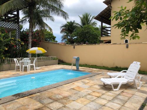 uma piscina com duas cadeiras e um guarda-sol em Casa Sol e Mar Jaconé: Um paraíso entre o mar e a lagoa em Jaconé