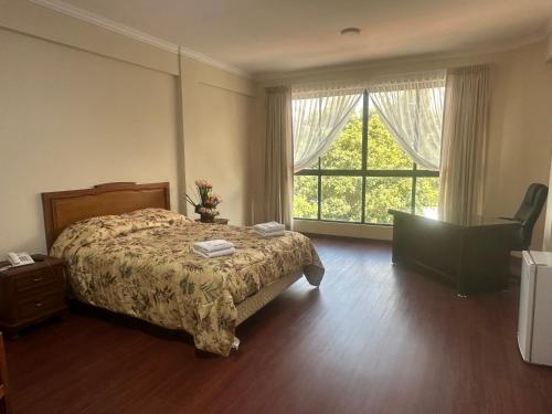 a bedroom with a bed and a large window at Hotel Oblitas in Cochabamba