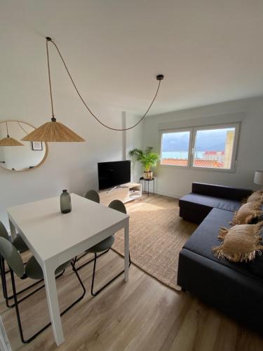 sala de estar con mesa blanca y sofá en Apartamento en Santander con vistas al mar, en Santander