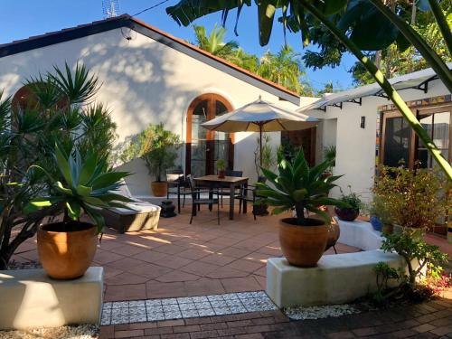 a patio with potted plants and an umbrella at Beach Bliss - Tropical tranquility, 3 mins walk to beach in Suffolk Park