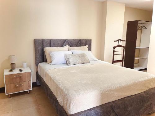 ein Schlafzimmer mit einem großen Bett und einem Nachttisch in der Unterkunft Departamento con jacuzzi, balcón, lavadora y garage in Ambato