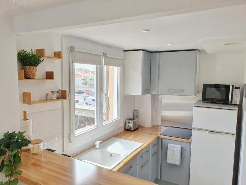 une cuisine blanche avec un évier et une fenêtre dans l'établissement Studio Cosy & Lumineux *Centre ville Cannes*, à Cannes