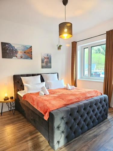 a bedroom with a large bed with an orange blanket at Design-Apartment I Black Forest I Boxspring I Nespresso I Spielplatz in Oberharmersbach
