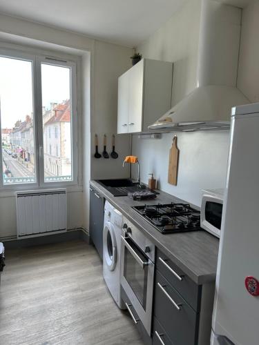 une cuisine avec une cuisinière et une machine à laver dans l'établissement F2 hyper centre ville Lons, à Lons-le-Saunier