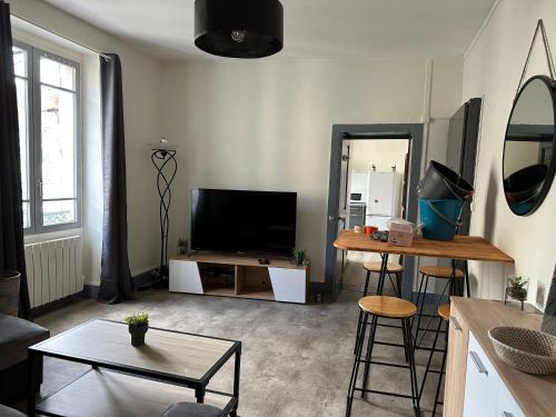 un salon avec une télévision et une table dans l'établissement F2 hyper centre ville Lons, à Lons-le-Saunier