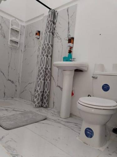 a white bathroom with a toilet and a sink at Casa Cala in Bribri