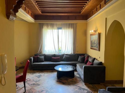a living room with a couch and a table at Appartement des palmiers avec piscine in Marrakech