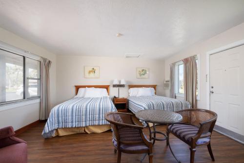 two beds in a room with a table and chairs at Suwannee Gables in Old Town