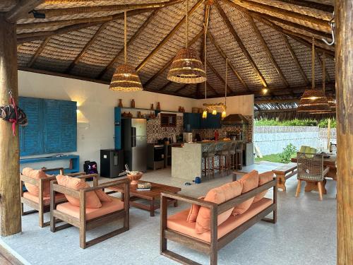 a living room with wooden furniture and a kitchen at Casa Tajo - Atins in Atins