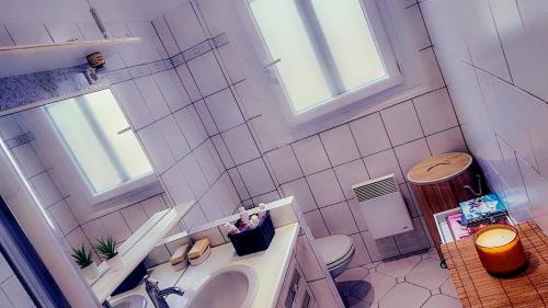 ein Bad mit einem Waschbecken, einem WC und Fenstern in der Unterkunft appartement cosy Asnières-sur-Seine in Asnières-sur-Seine