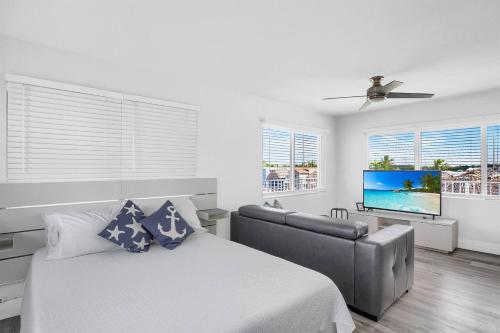 een slaapkamer met een bed, een bank en een televisie bij Waterfront Studio 2, Couples Oasis, Kayaks, Pool in Jewfish