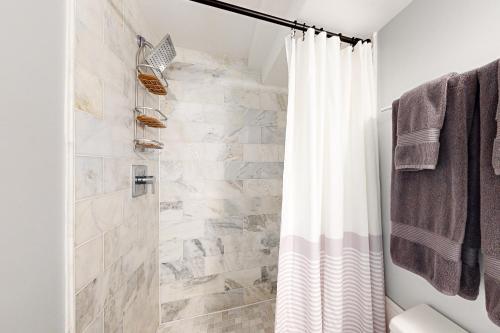 a bathroom with a shower with a white shower curtain at Downtown Retreat - Your Urban Oasis in College Park