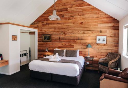 a bedroom with a bed and a wooden wall at Cottages at Kinross in Gibbston