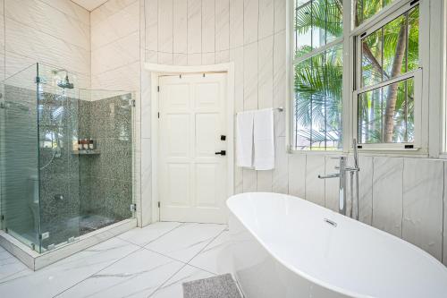 La salle de bains blanche est pourvue d'une baignoire et d'une douche. dans l'établissement Casa Reina Main House & Casita, à Playa Hermosa