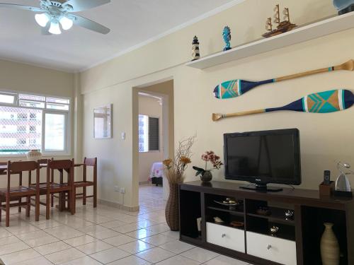 a living room with a tv and a baseball bat on the wall at APARTAMENTO NA PRAIA GRANDE A 200 MÉTROS DA PRAIA, CONFORTÁVEL ESPAÇOSO WIFI 350 Mega TV Claro, ÓTIMA LOCALIZAÇÃO in Praia Grande