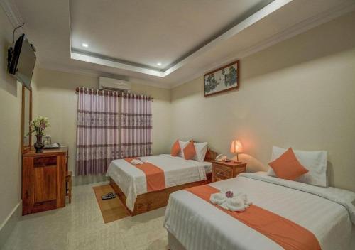 una camera d'albergo con due letti e una televisione di Punleu Raksmey Boutique a Siem Reap