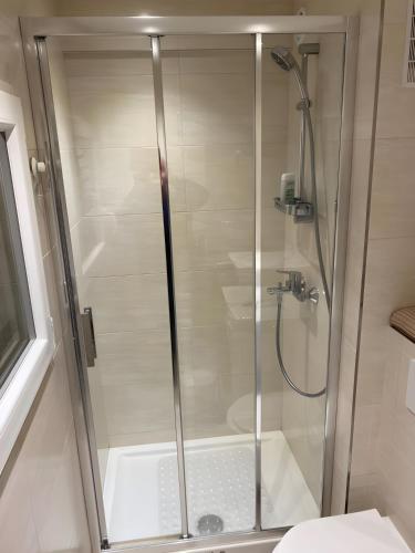 une douche avec une porte vitrée dans une salle de bain dans l'établissement Studio à proximité immédiate des transports avec une terrasse, à Cachan
