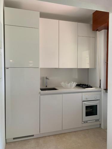 a white kitchen with white cabinets and a sink at Cala dei Pirati in Punta Ala