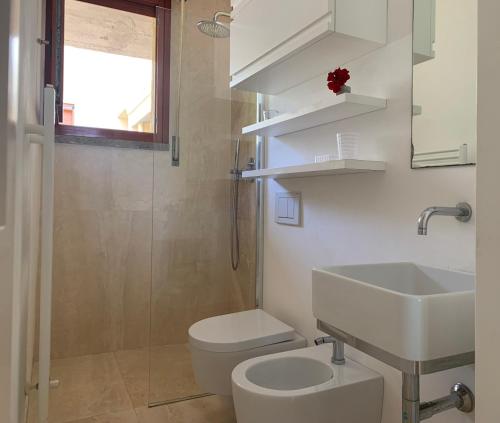a white bathroom with a sink and a toilet at Cala dei Pirati in Punta Ala