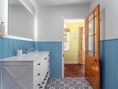 baño con lavabo y pared azul en Crabapple Cottage - Coromandel Town Holiday Home, en Coromandel
