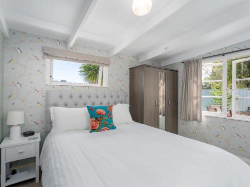 1 dormitorio con cama blanca y ventana en Crabapple Cottage - Coromandel Town Holiday Home, en Coromandel