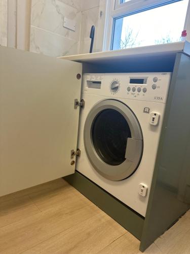 a washing machine in a room with a window at Japandi themed London Apartment in Thornton Heath