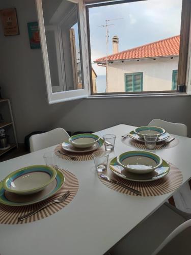 a dining room table with plates and glasses and a window at Casa Seamus Briatico in Briatico