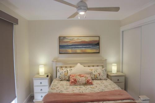 a bedroom with a bed with a ceiling fan at Palm Breeze at Sunset Strip in Sunset Strip