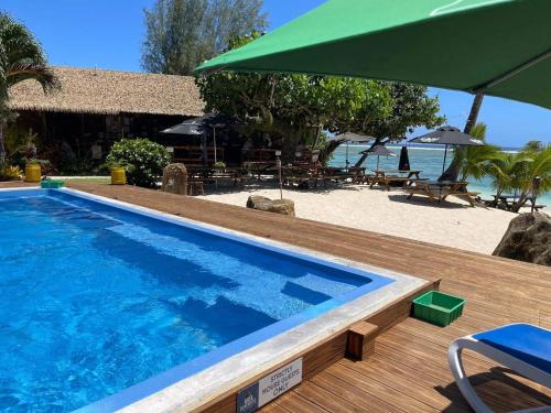 a swimming pool next to a beach with an umbrella at Aroa Beachside Resort in Rarotonga